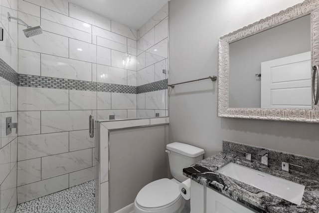 bathroom with toilet, vanity, and a shower with door