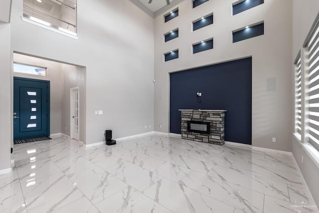 unfurnished living room with a high ceiling and a stone fireplace