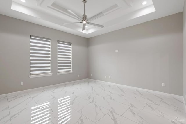 spare room featuring a tray ceiling and ceiling fan