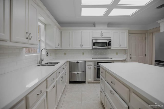 kitchen with appliances with stainless steel finishes, a sink, light countertops, and decorative backsplash