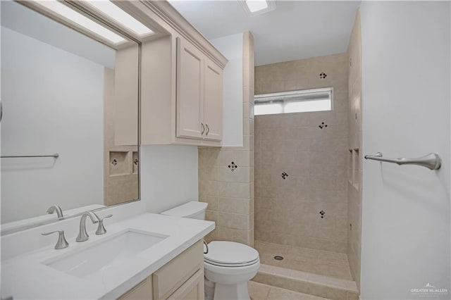 bathroom with a tile shower, toilet, and vanity