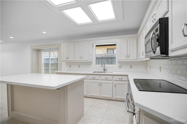 kitchen with stainless steel microwave, a sink, tasteful backsplash, light countertops, and recessed lighting