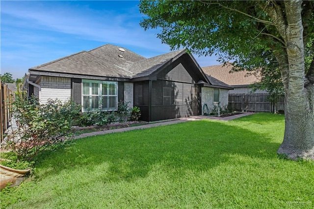 back of property with brick siding, roof with shingles, and a sunroom