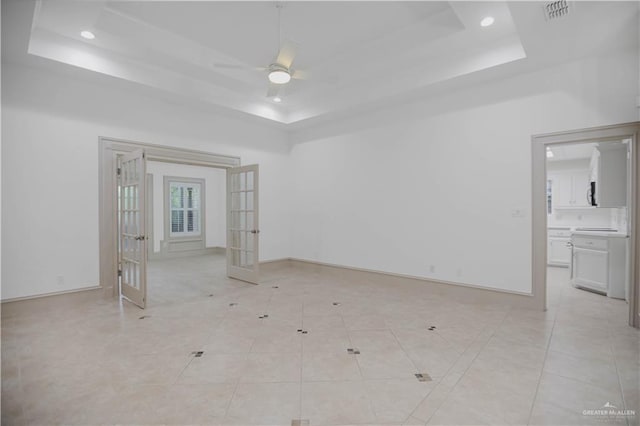 empty room featuring a tray ceiling, french doors, ceiling fan, baseboards, and recessed lighting