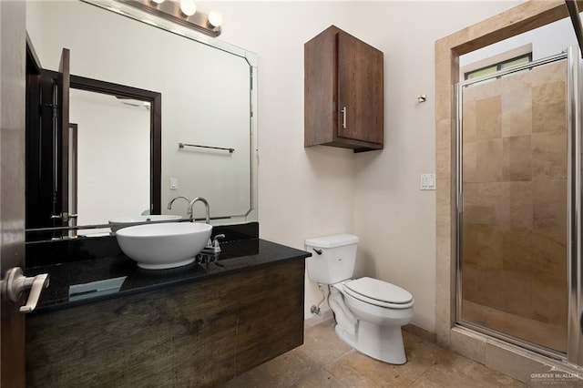 bathroom featuring tile patterned flooring, toilet, a shower with shower door, and sink