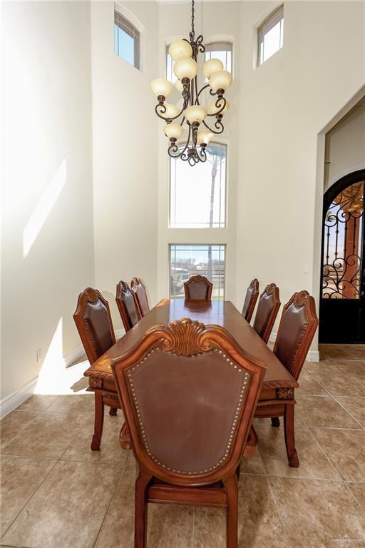 dining area with arched walkways, a high ceiling, a wealth of natural light, and a notable chandelier