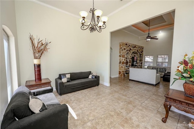 living area featuring baseboards, arched walkways, a towering ceiling, ornamental molding, and ceiling fan with notable chandelier