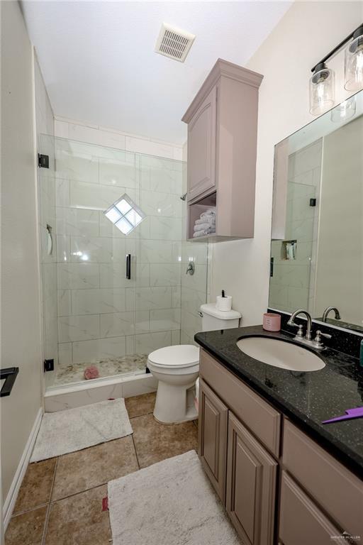 bathroom with toilet, a stall shower, visible vents, and vanity