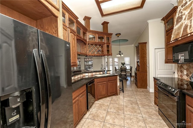 kitchen featuring light tile patterned floors, brown cabinetry, backsplash, black appliances, and a sink