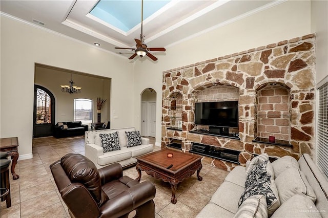 living area featuring visible vents, arched walkways, a raised ceiling, ornamental molding, and tile patterned floors