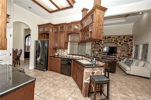 kitchen with arched walkways, decorative backsplash, ornamental molding, a sink, and black appliances