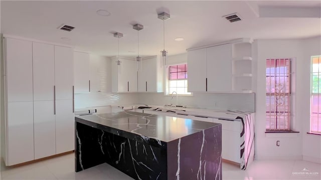 kitchen featuring white cabinetry, backsplash, hanging light fixtures, a center island, and light tile patterned floors