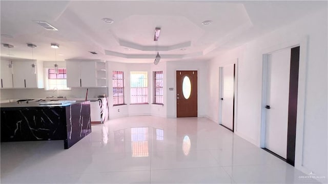 entryway featuring light tile patterned floors, a tray ceiling, and sink