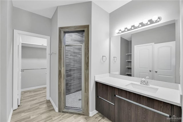 bathroom with a shower with door, vanity, and wood-type flooring