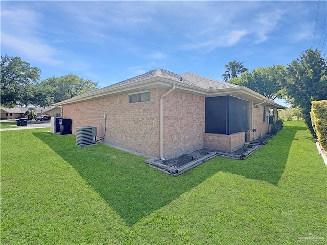 view of home's exterior featuring a lawn, central AC, and brick siding