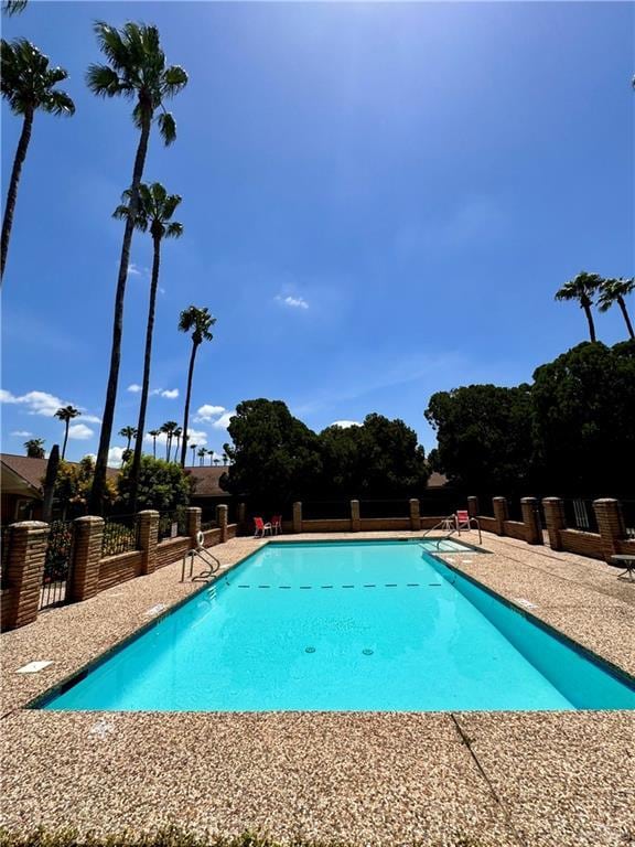 pool with a patio area and fence