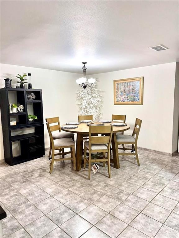 dining space featuring a chandelier, visible vents, a textured ceiling, and light tile patterned floors