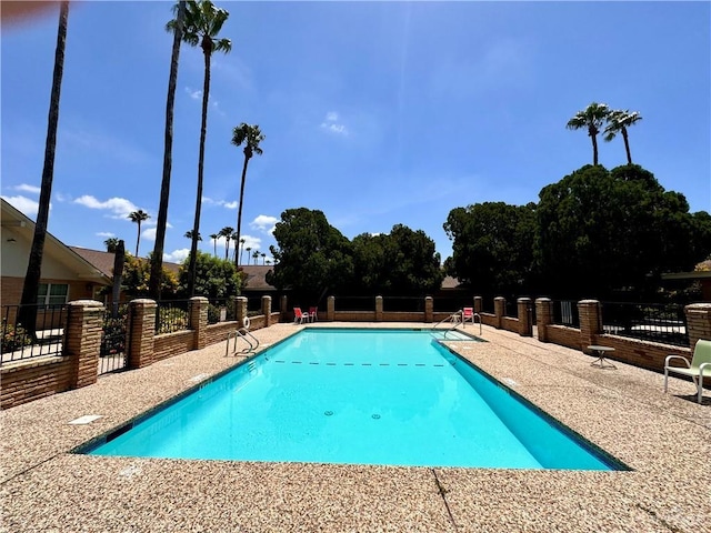 community pool with a patio and fence