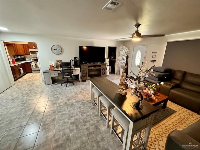 living area with light tile patterned floors, a ceiling fan, and visible vents