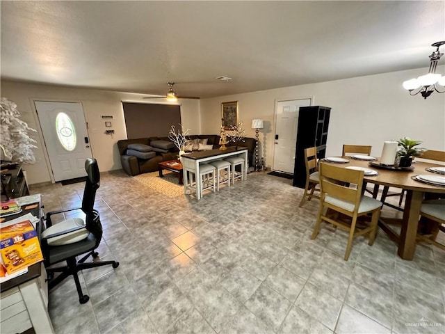 dining space with ceiling fan with notable chandelier