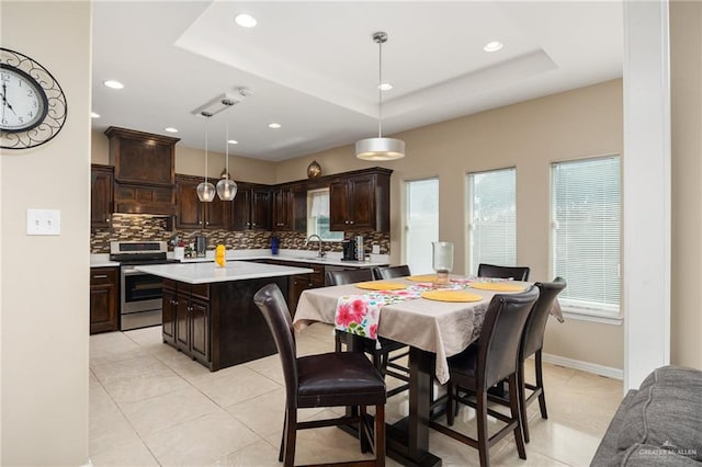 tiled dining space featuring a raised ceiling