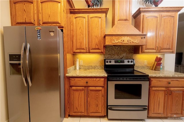 907 Amethyst Dr, Weslaco, TX 78596 - kitchen with appliances with stainless steel finishes, custom range hood, tasteful backsplash, light stone counters, and brown cabinetry