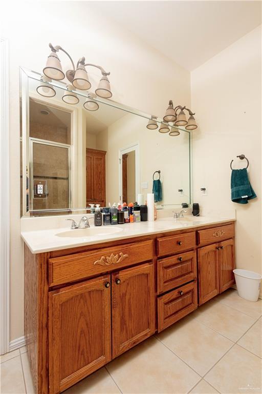 907 Amethyst Dr, Weslaco, TX 78596 - bathroom with tile patterned flooring, double vanity, a shower stall, and a chandelier