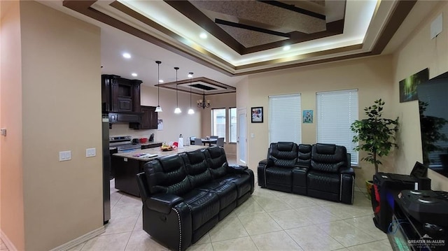 living room with an inviting chandelier, light tile patterned floors, and a tray ceiling