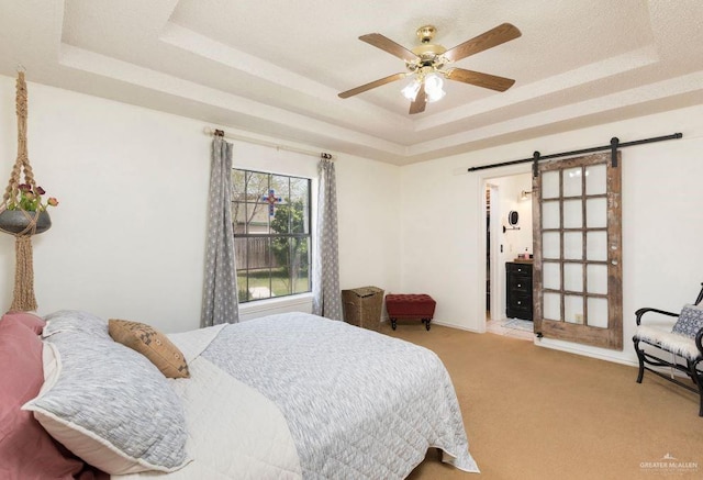 bedroom with a tray ceiling, carpet flooring, ceiling fan, and a barn door