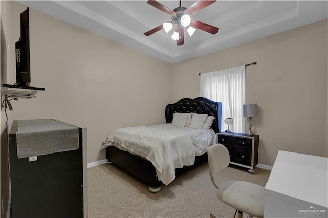 bedroom featuring a tray ceiling, ceiling fan, and light carpet