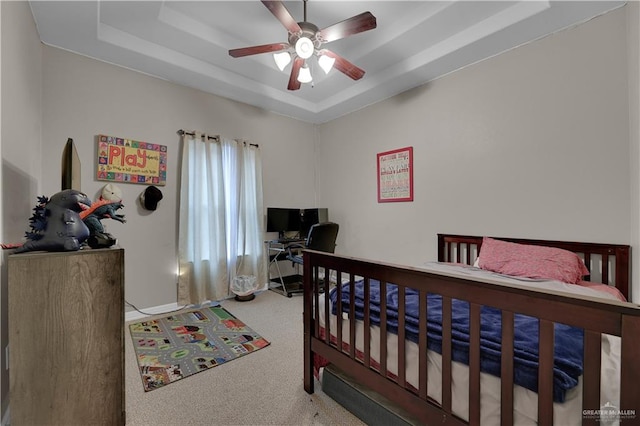 carpeted bedroom featuring a raised ceiling and ceiling fan