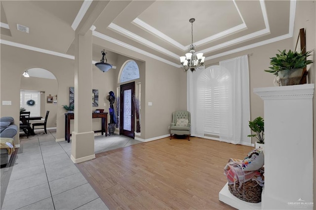 entrance foyer with french doors, an inviting chandelier, a raised ceiling, light hardwood / wood-style flooring, and ornamental molding