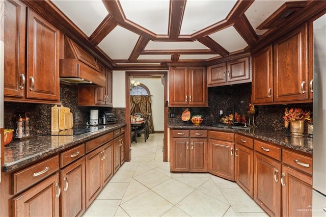 kitchen featuring sink, coffered ceiling, dark stone countertops, decorative backsplash, and black electric stovetop