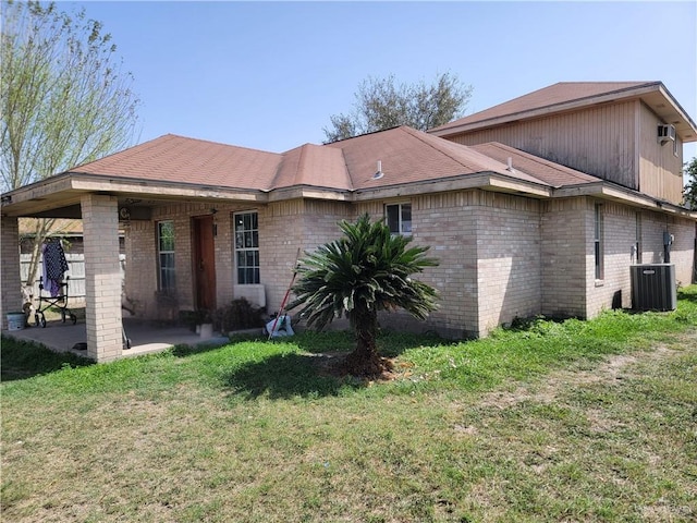 back of house featuring central AC unit, a lawn, a patio area, and brick siding