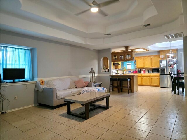 living area featuring a ceiling fan, a tray ceiling, and visible vents