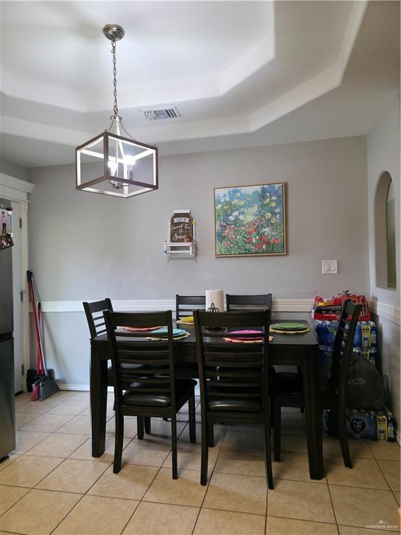 dining space featuring visible vents, a raised ceiling, and light tile patterned floors