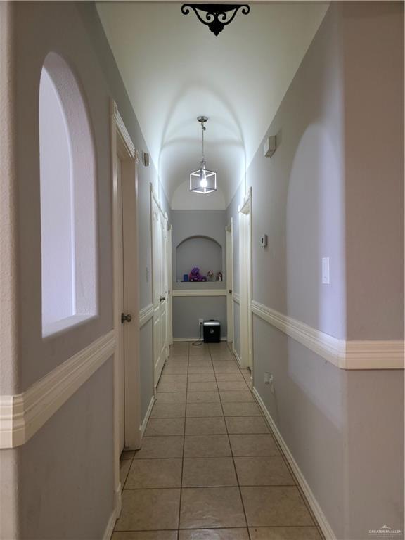 hallway featuring baseboards, arched walkways, and light tile patterned floors