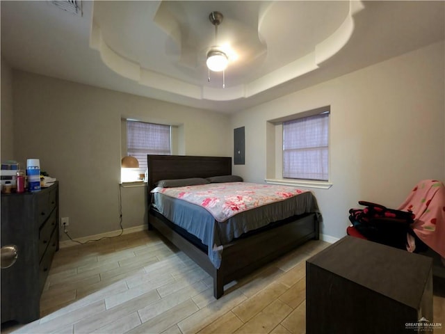 bedroom with wood tiled floor, baseboards, a tray ceiling, and electric panel