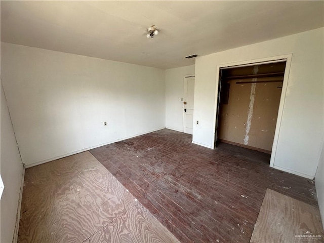 unfurnished bedroom featuring a closet and dark wood-type flooring