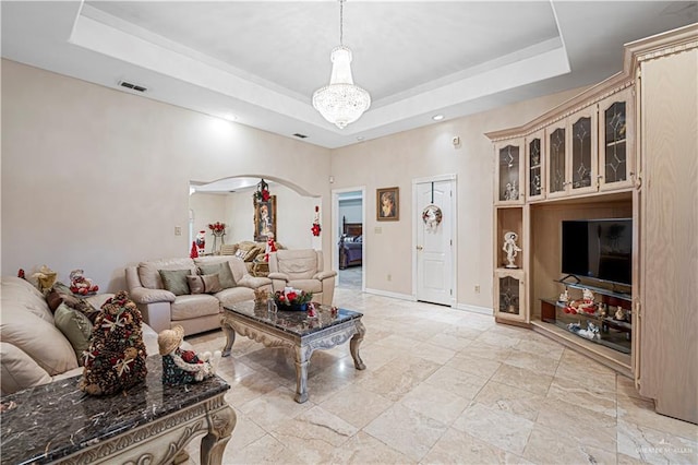 living room with a raised ceiling and a chandelier