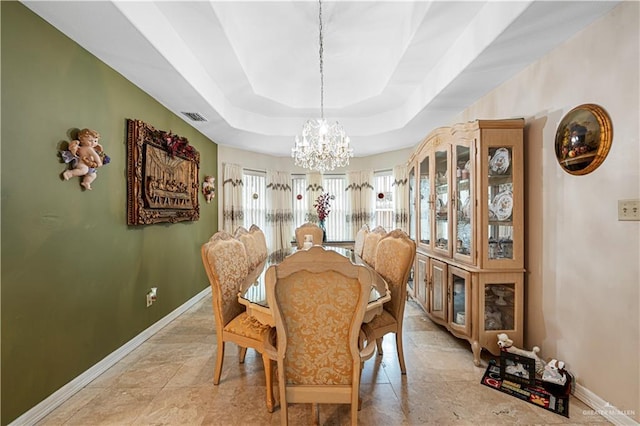 dining area featuring a chandelier, a tray ceiling, and light tile patterned flooring