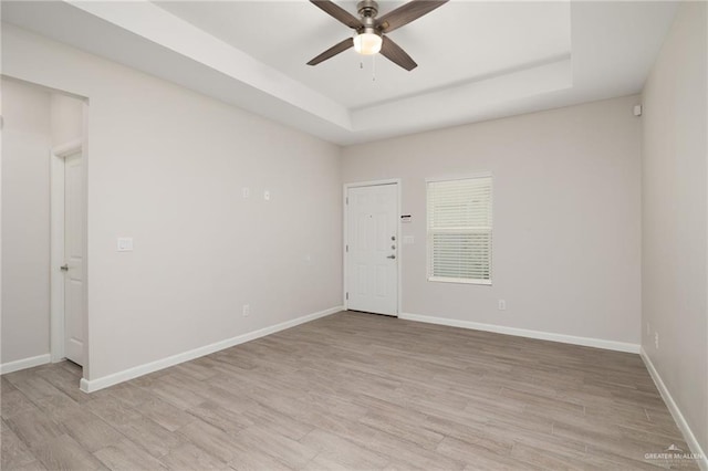 unfurnished room with a tray ceiling, ceiling fan, and light hardwood / wood-style flooring