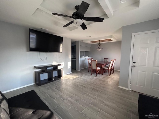 living area featuring wood tiled floor, baseboards, a raised ceiling, and a ceiling fan