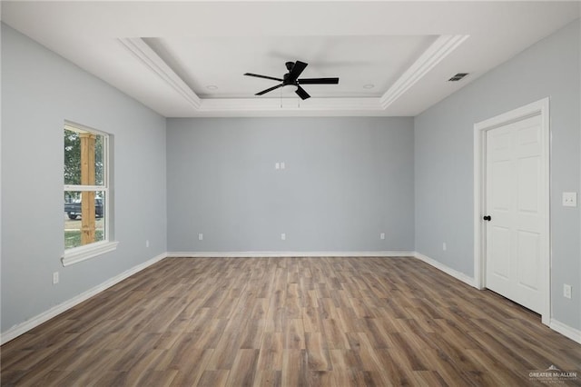 unfurnished room with a ceiling fan, a raised ceiling, baseboards, and wood finished floors