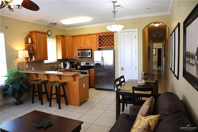 131 E Saturn Ln Unit 3, South Padre Island, TX 78597 - kitchen with stainless steel appliances, arched walkways, a peninsula, a sink, and a kitchen breakfast bar