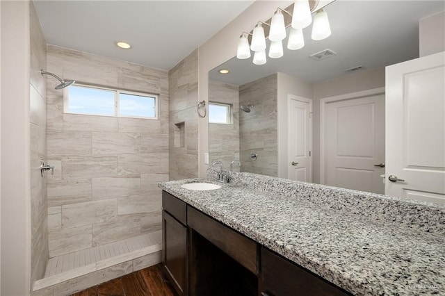 bathroom featuring hardwood / wood-style flooring, vanity, and a tile shower