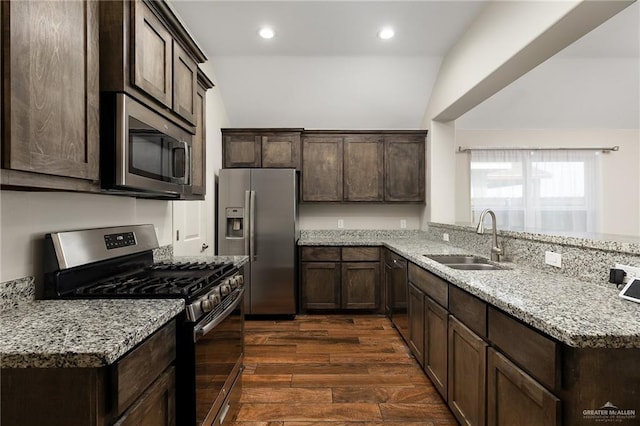 kitchen with sink, stainless steel appliances, dark hardwood / wood-style floors, light stone countertops, and vaulted ceiling