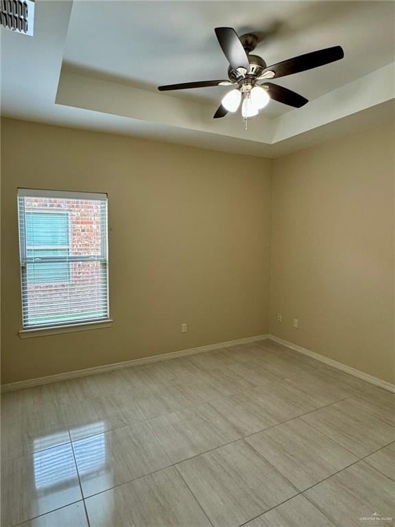 unfurnished room featuring light tile patterned floors, visible vents, a tray ceiling, baseboards, and a ceiling fan
