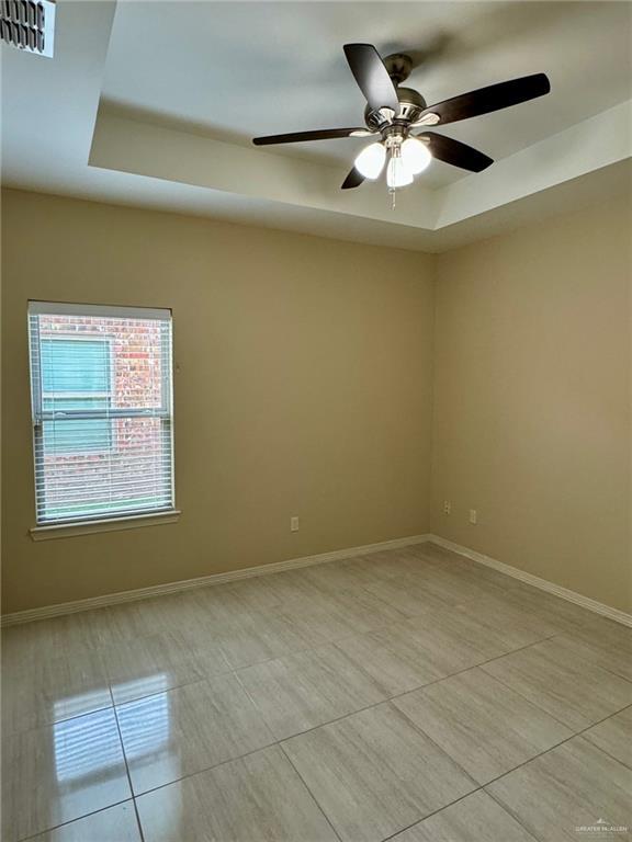 2611 E Eisenhower Ave, Mission, TX 78573 - unfurnished room featuring light tile patterned floors, visible vents, a tray ceiling, baseboards, and a ceiling fan