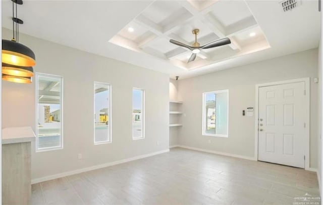 empty room featuring ceiling fan, light hardwood / wood-style floors, a wealth of natural light, and coffered ceiling